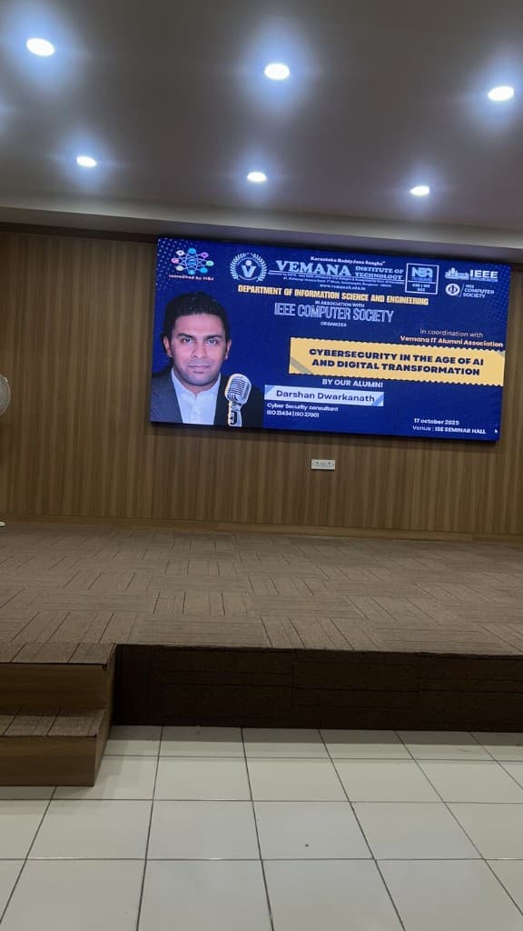 Seminar hall screen showing event poster for alumni cybersecurity talk